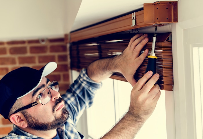 Man in hat and glasses installing blinds
