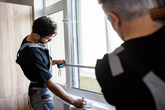 Two workers measuring windows for a project