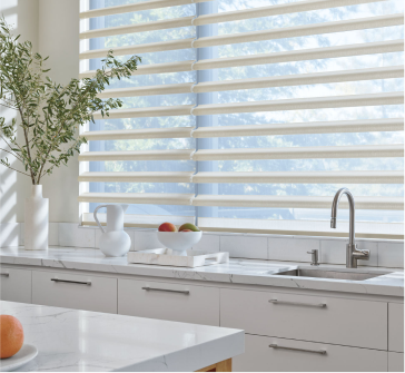 Sheer horizontal shades in a bright kitchen allow filtered sunlight while maintaining an airy and open feel