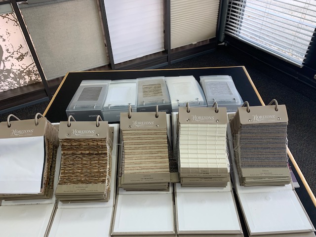 Display of Horizons fabric and material samples for custom blinds and shades, showcasing textures, colors, and patterns for customers to experience quality firsthand