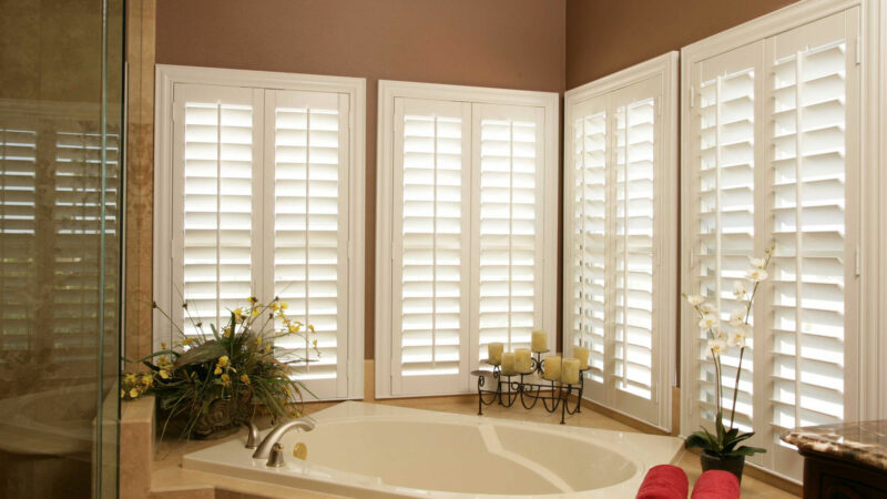 Luxurious bathroom with white shutters surrounding a soaking tub