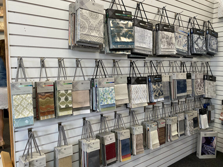 A display wall of hanging fabric swatches in various patterns and colors used for in-depth demonstrations of custom window treatments