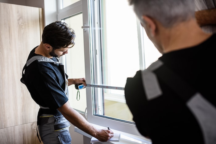 Two workers measuring a window frame to install cordless blinds for precise fit and clean finish