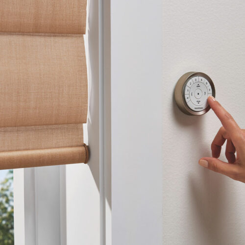 Hand adjusting a wall-mounted remote control for automated window coverings