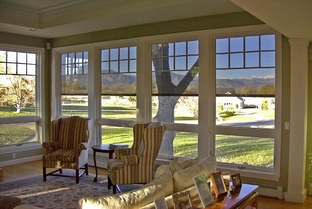 Sunroom with striped armchairs and large windows fitted with light-filtering solar shades