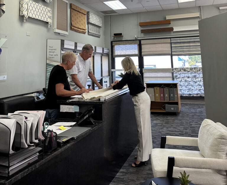 Two women reviewing fabric swatches during a personalized window treatment consultation, with staff providing guidance on design and material options
