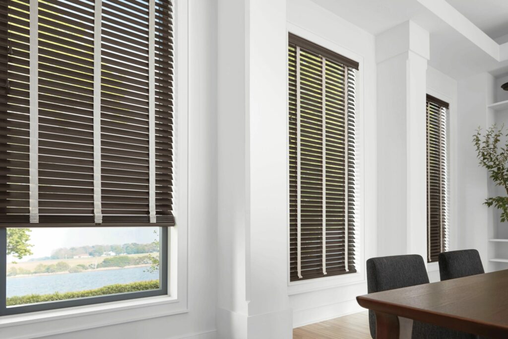 Home office with windows featuring faux wood blinds.
